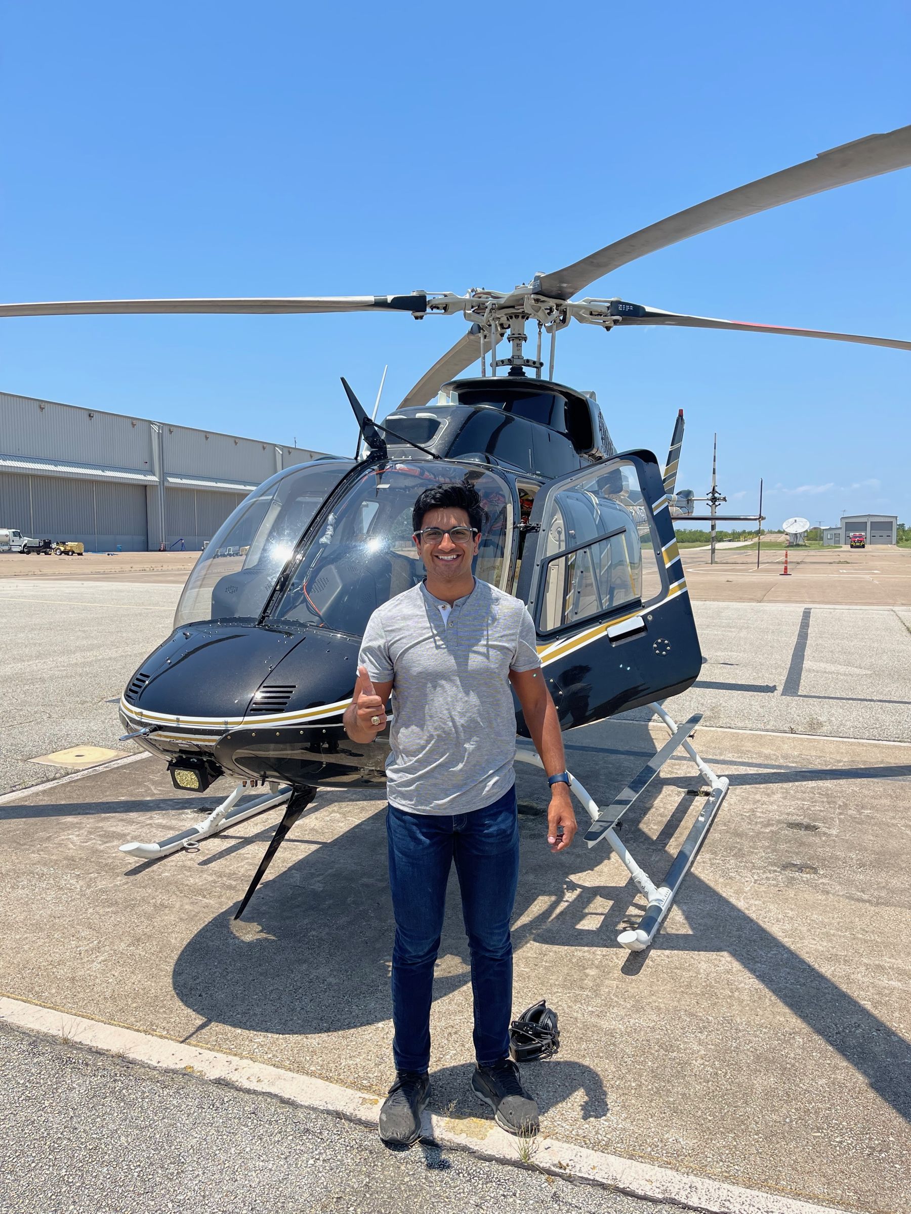 Akku giving a thumbs up in front of a helicopter on an airport ramp