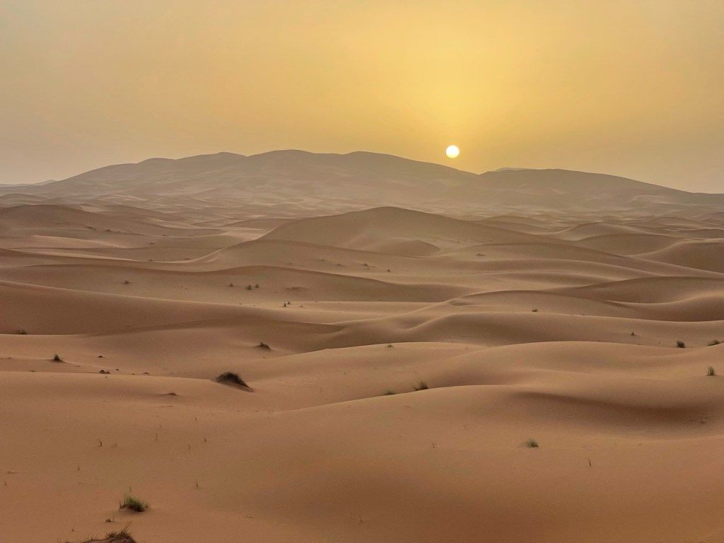 Sand dunes under a hazy setting sun